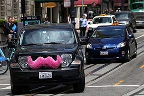 A Lyft car, with its trademark pink &quot;mustache,&quot; drives along Powell Street in San Francisco, in June 2014. Lyft is a service where people use their own cars to transport strangers for pay.