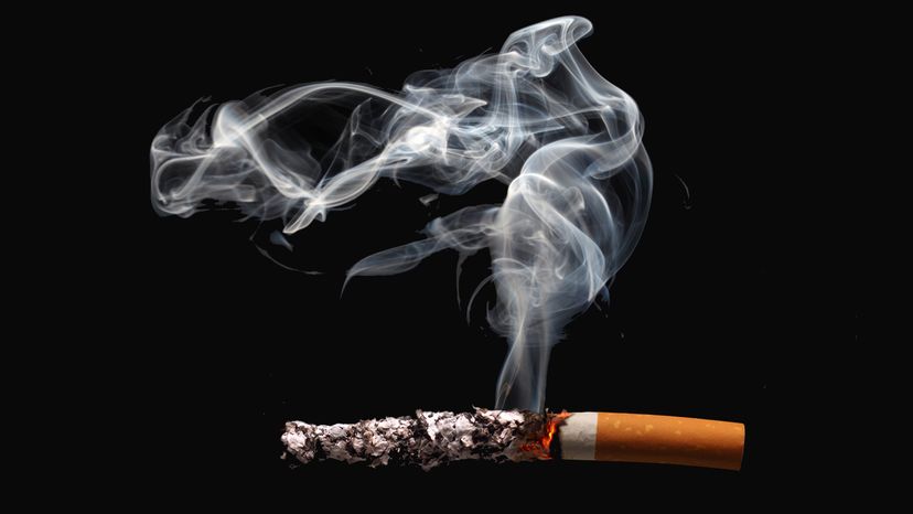 A cigarette with long ash against a black background.