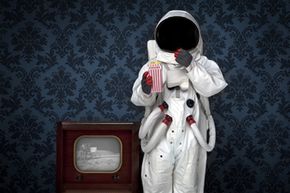 An astronaut watches the moon landing on television.