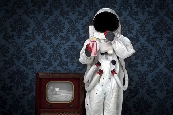 An astronaut watches the moon landing on television. 