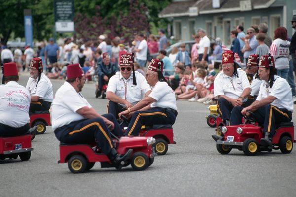 Shriners wearing fezzes ride miniature cars during a Memorial Day parade in Mystic, Connecticut