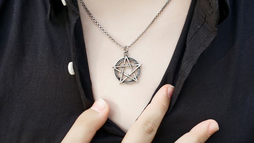 Close-up of a pentacle pendant hanging from a chain on someone's neck