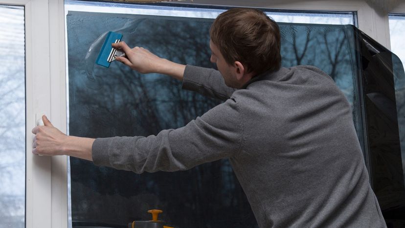 A man installing plastic window film on a window.&nbsp;