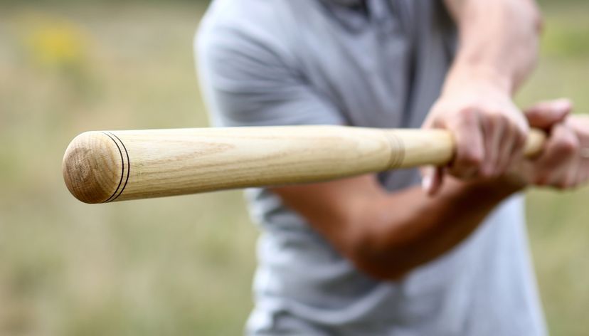 A close up of a man swinging a wooden baseball bat.