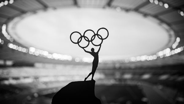 Statue of Athlete Holds Olympic Circle High at Modern Olympic Stadium