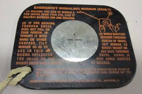 The reverse of an emergency signaling mirror issued to pilots for use in the 1940s. Note the instructions on how to use it.