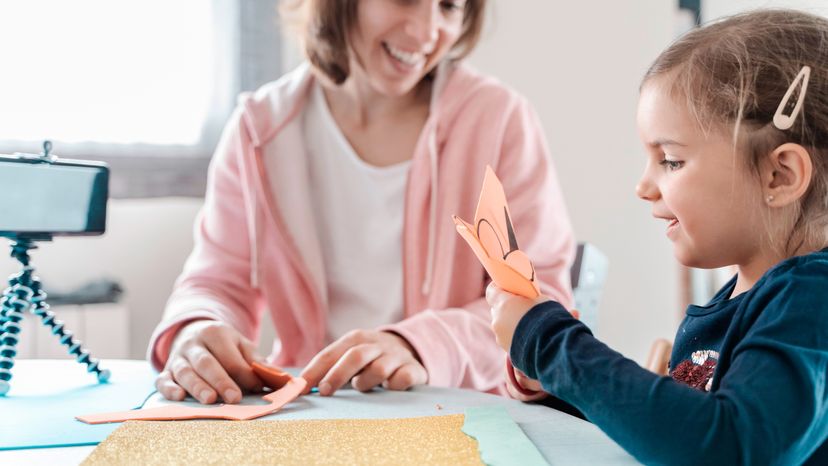 A mother helping her child make an artwork.