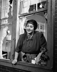 Gertrude Berg smiles as she leans out of a window in a scene from &quot;The Goldbergs,&quot; the first sitcom.