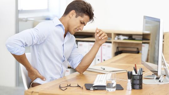 Why is sitting in a chair for long periods bad for your back?