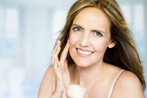 Woman is applying cream to her face.