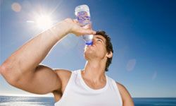 Man drinking bottle of water outdoors after workout