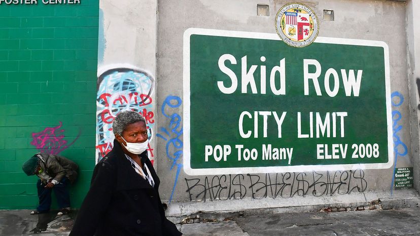 woman walks past a Skid Row sign