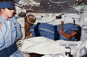 Pilot Michael L. Coats (left) and mission specialist Steven A. Hawley (right) fall asleep listening to music on the lower deck of the shuttle Discovery.