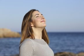 A woman breathes in air on the beach.