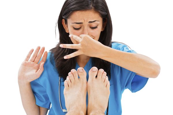 Doctor plugging nose over stinky feet