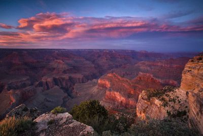 The sun sets in a clear sky over the Grand Canyon.
