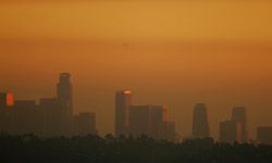 The skyline of downtown Los Angeles is lit up by the murky browns and reds of a smoggy sunset.