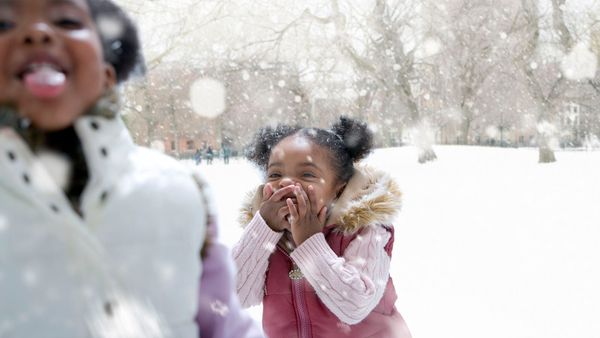 Child smiling in snowy winter outdoors.