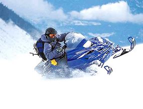 This snowmobiler leans into a sharp turn, which helps to keep him from flipping.