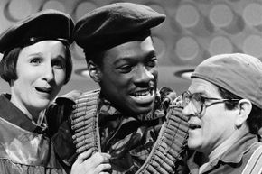 Three comedians embrace in a black-and-white still taken from a 'Saturday Night Live' episode.