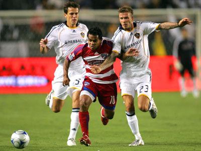 David Ferreira #10 of FC Dallas paces the ball past Stefani Miglioranzi #15 and David Beckham #23 of the Los Angeles Galaxy