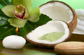 vocado coconut scrub in coconut shell, orchid flower (Cymbidium sp.), tropical plant, soap and aroma candle.