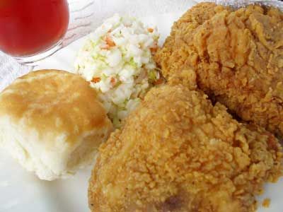 Kentucky fried chicken plate complete with bisquit, crispy chicken, slaw and iced tea on the side.