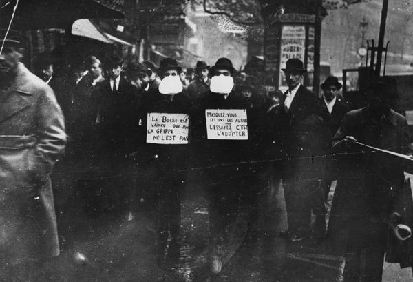 Two men wearing and advocating the use of flu masks in Paris during the Spanish flu epidemic which followed World War I.