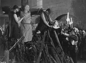 Circa 1933: British actor Matheson Lang is chained to a cross during the Spanish Inquisition in a scene from the film "The Wandering Jew."”border=