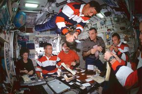 Crews from three different countries have a meal together at the International Space Station, 2001.