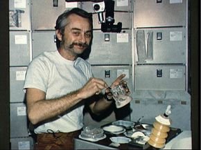 Skylab 3 Astronaut Owen Garriott reconstitutes food in the crew quarters.