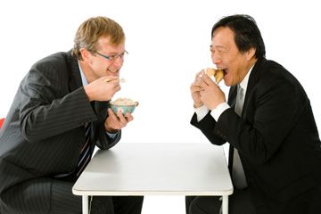 Caucasian man and Asian man eat rice and hamburger