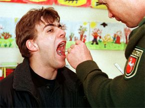 A German police officer takes a saliva sample from a young man at a primary school in northwestern Germany. The country has used voluntary genetic testing as an unprecedented evidence-gathering technique.