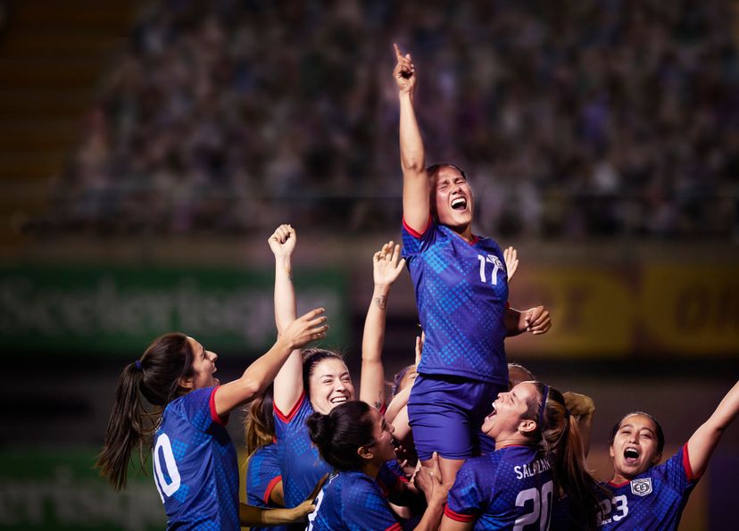 Elated team of athletic women footballers cheeringly lift up their teammate and celebrate after an important win