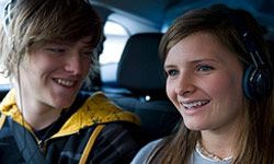 Teens listening to headphones in car. 