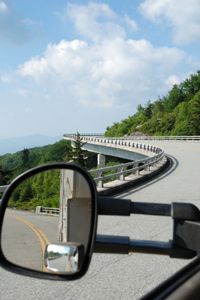 A curvy mountain road ahead of a truck and trailer.