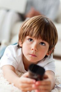 Little boy holding a remote lying on the floor