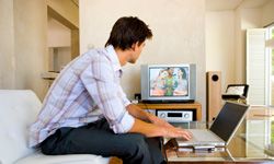 man with a laptop watches television