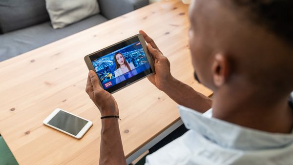 A man watching Tv on his phone