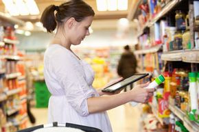 Woman using a tablet while shopping for groceries.