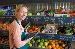 Grocer in front of produce, holding a tablet