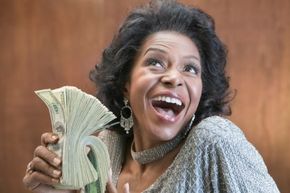 A woman holding a stack of 100 dollar bills.