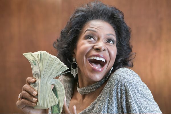 A woman holding a stack of 100 dollar bills.