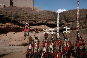 Dogon tribespeople dressed for a funeral. Two people (back row, third from right and all the way on the right) appear to be wearing sirige masks.