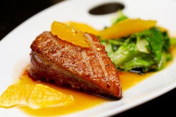Duck breast with greens, sauce and supremes of citrus.