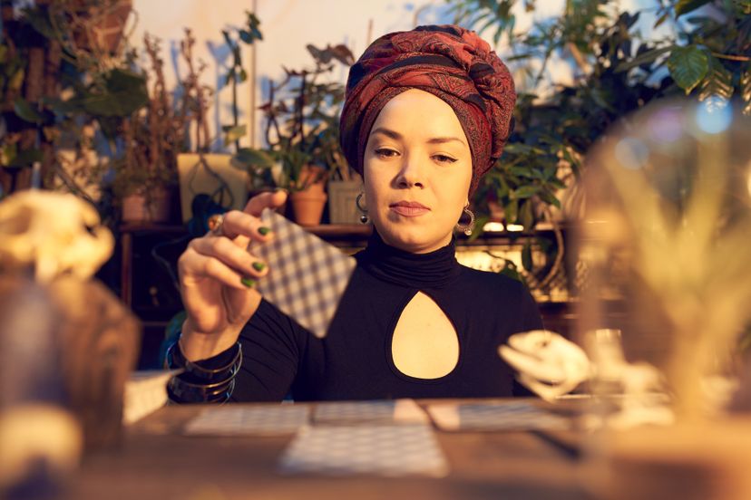 Female fortune teller sitting at table and reading tarot cards