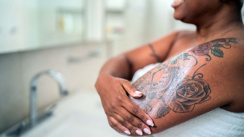 Woman applying body mosture in the bathroom at home