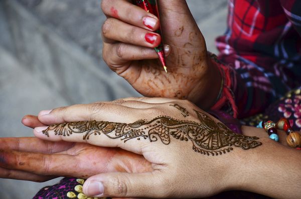 Someone gets a henna tattoo. 