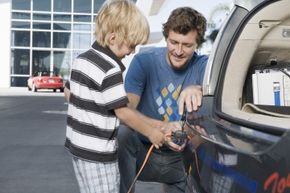 Man and son plug in electric car