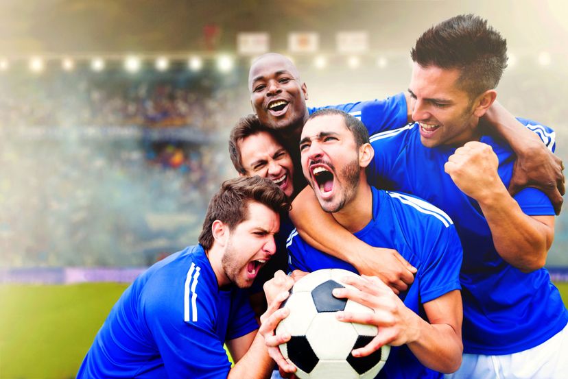 Happy football team celebrating a goal at the stadium